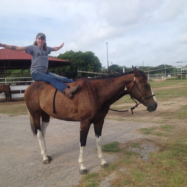 horseback riding student practices some yoga on registered paint mare during summer camp program at Round Rock horseback riding facility