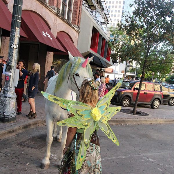 Austin fairy and SXSW unicorn pause for a quick kiss on the streets of downtown Austin