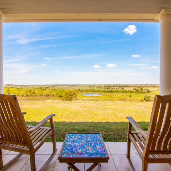 Two rocking chairs and beautiful mosaic tile table bundled up nice and cozy on the porch of this Texas dude ranch home