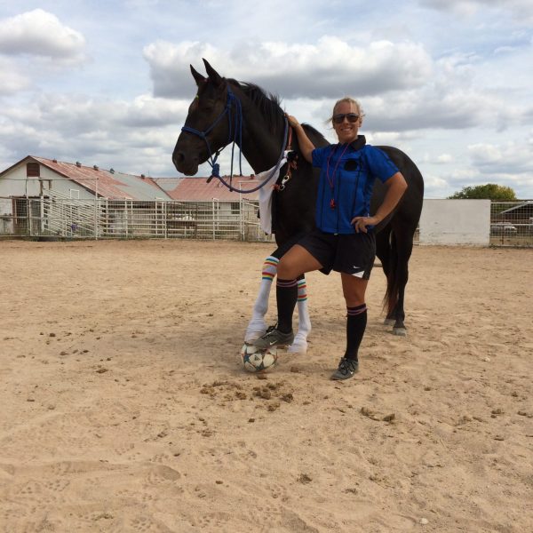 MacCoy and black stand with foot and hoof placed over soccer ball during summer camp activities in Austin Texas 2016