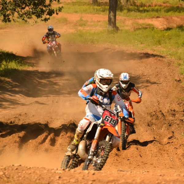 Dirtbike rider in white helmet hits the curve of race track in Central Texas